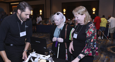 NFB members get a demonstration of a device in the exhibit hall.