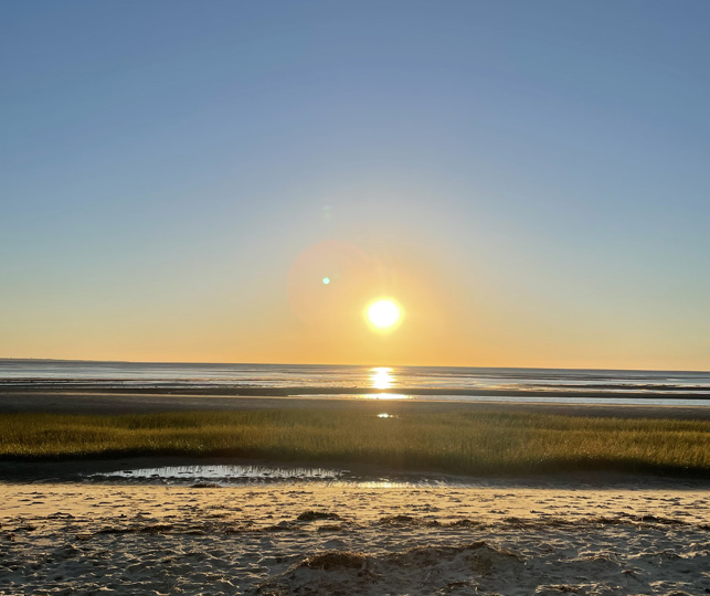 The sun begins to set over a Cape Cod, MA beach.